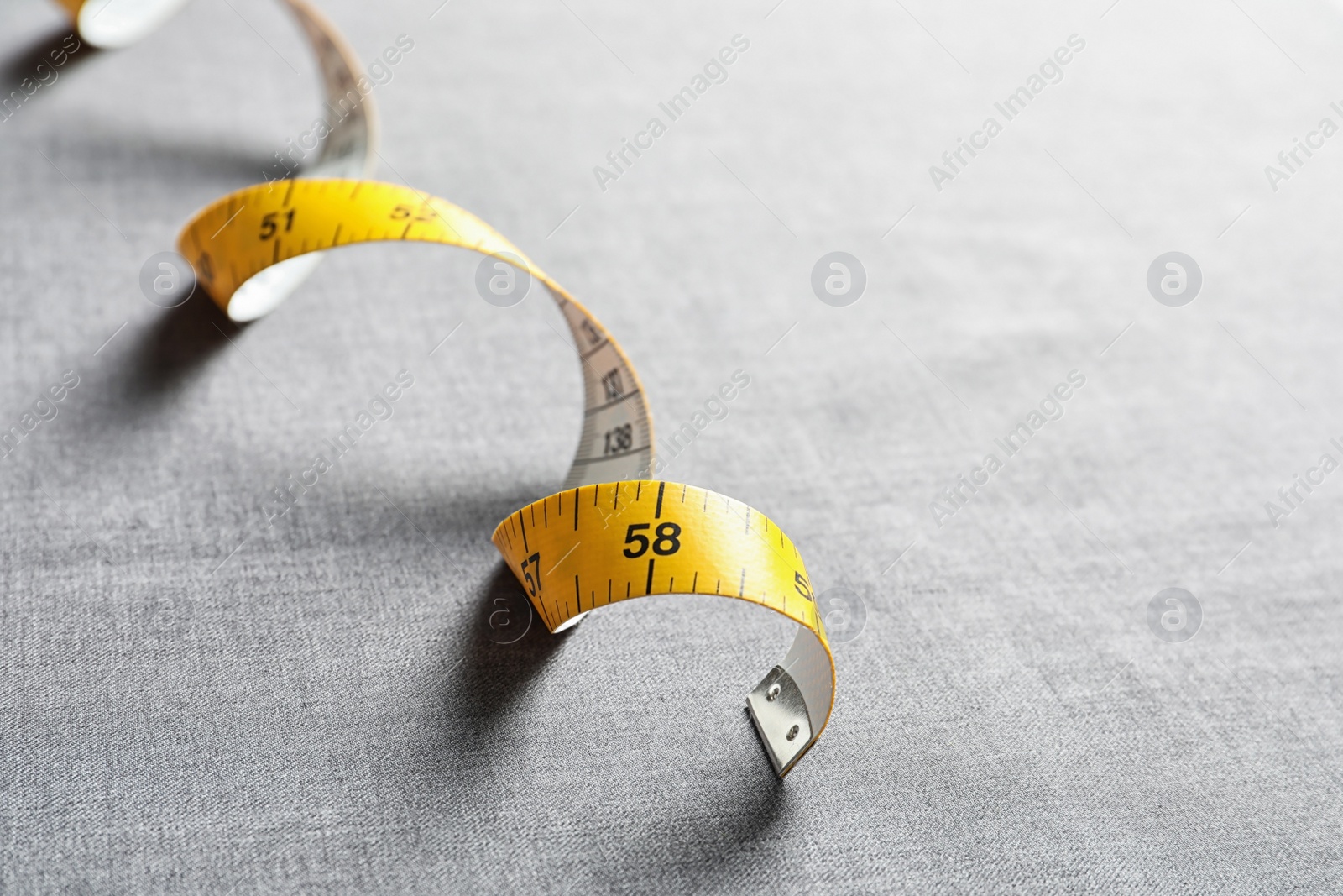 Photo of Measuring tape on grey fabric. Tailoring equipment