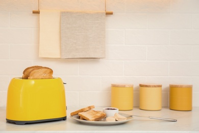 Photo of Modern toaster and tasty breakfast on counter in kitchen