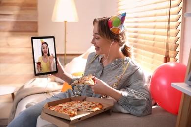 Image of Woman with piece of pizza having online party via tablet at home during quarantine lockdown 