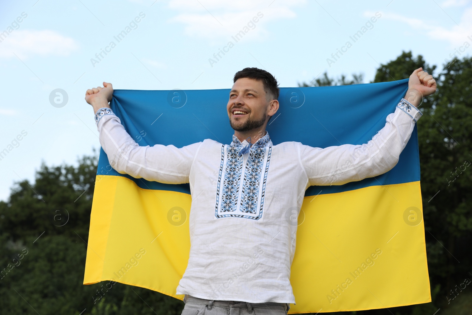 Photo of Man in vyshyvanka with flag of Ukraine outdoors