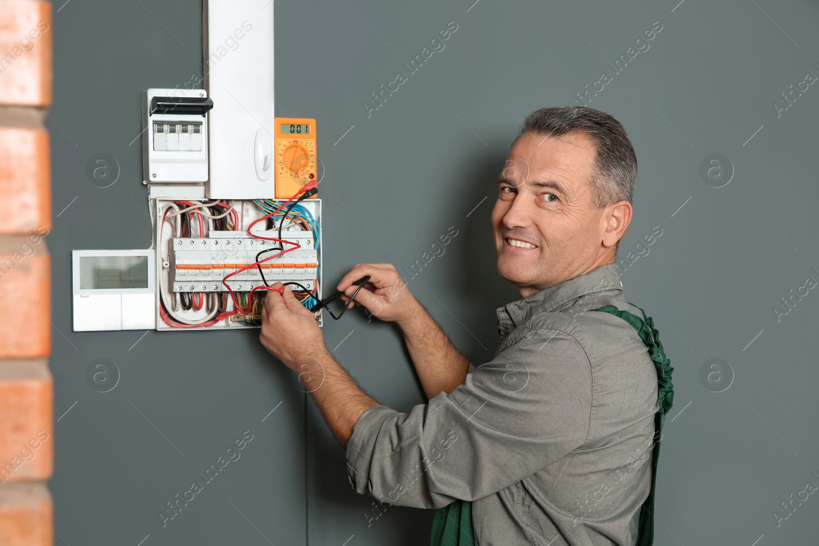 Photo of Professional electrician with tester checking voltage indoors