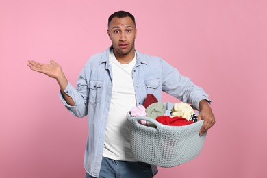 Photo of Young man with basket full of laundry on pink background