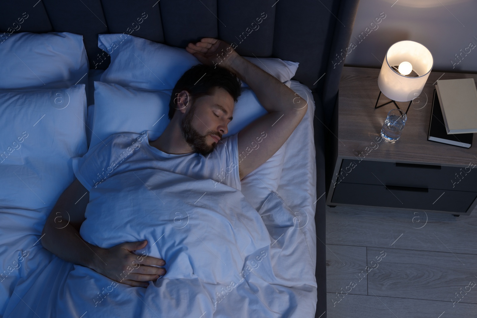 Photo of Man sleeping in bed at night, above view