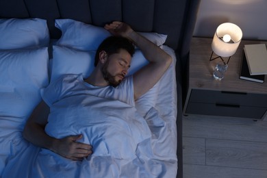 Photo of Man sleeping in bed at night, above view