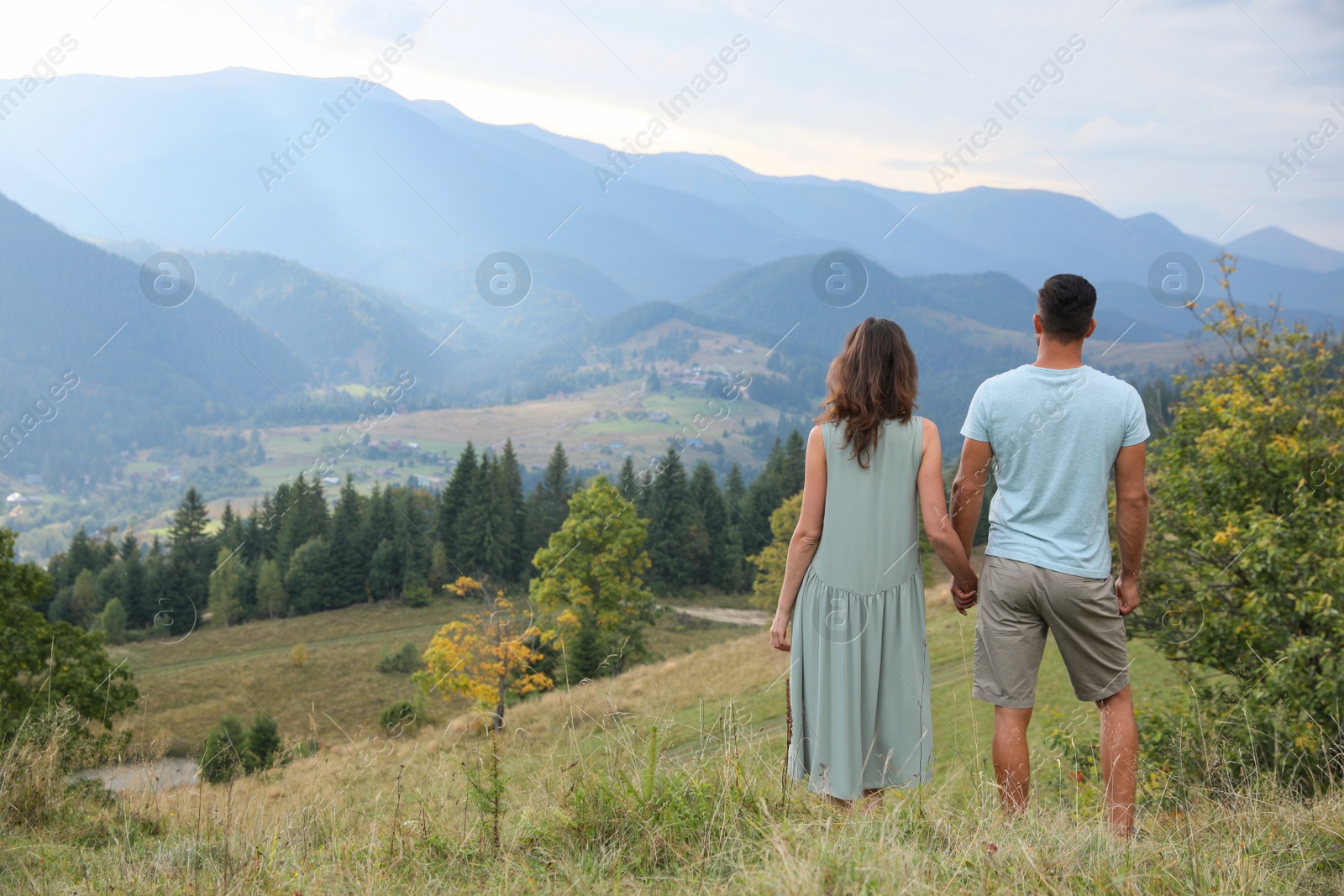 Photo of Couple enjoying beautiful mountain landscape, back view. Space for text