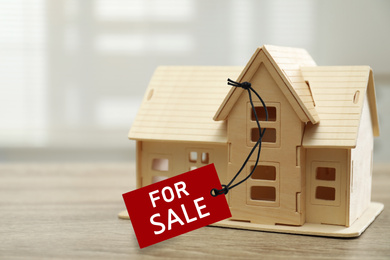 Image of Wooden house model with SALE label on table