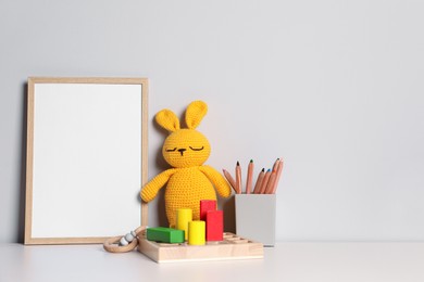 Empty square frame, stationery and different toys on white table, space for text