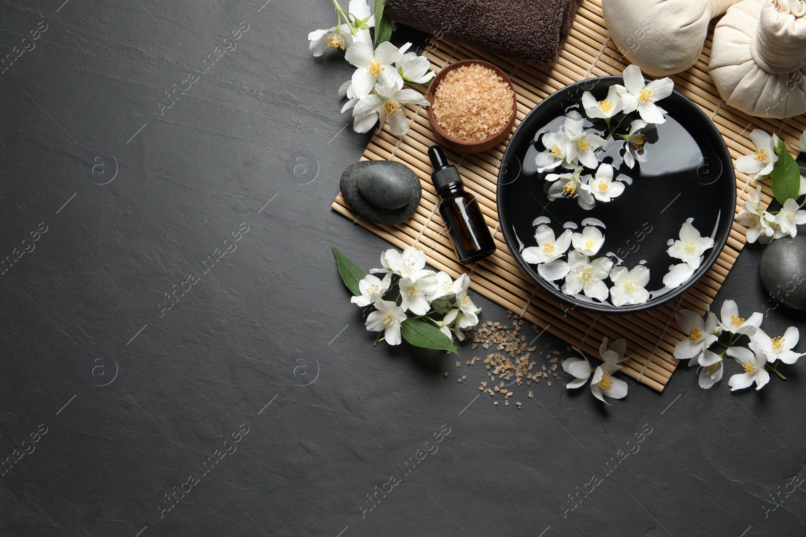 Photo of Beautiful spa composition with jasmine essential oil and fresh flowers on table, flat lay. Space for text