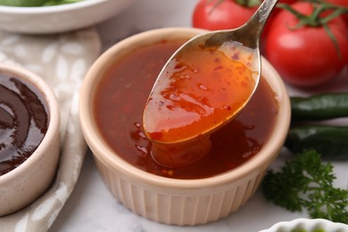 Photo of Taking homemade marinade from bowl at table, closeup