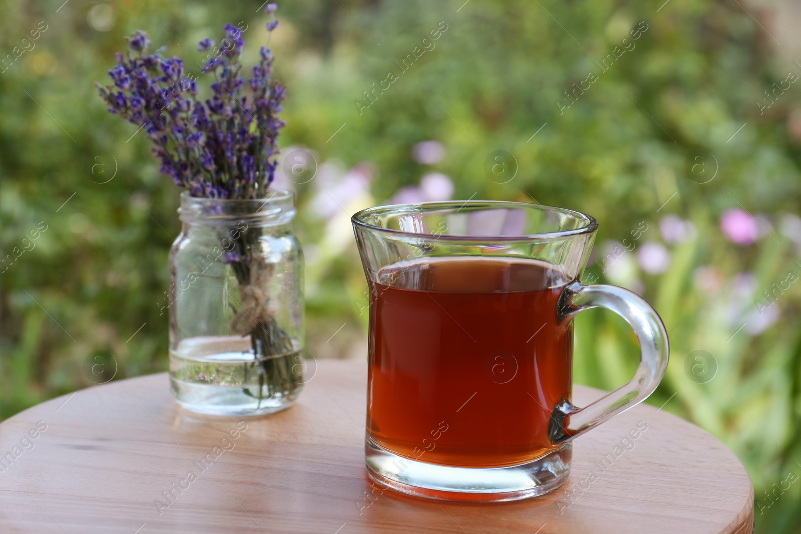 Photo of Beautiful lavender flowers and cup of aromatic tea on wooden table