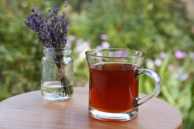 Photo of Beautiful lavender flowers and cup of aromatic tea on wooden table