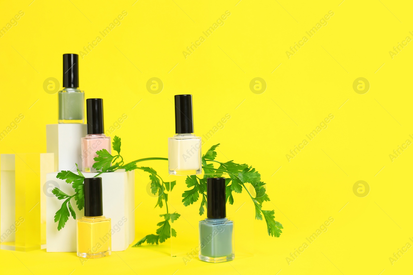 Photo of Stylish presentation of beautiful nail polishes in bottles on yellow background