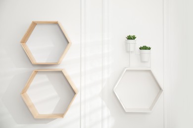 Photo of Honeycomb shaped shelves with plants on white wall