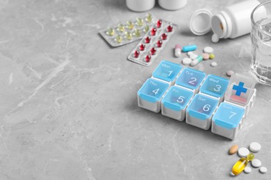 Weekly pill box with medicaments on grey marble table. Space for text