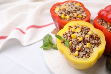 Photo of Quinoa stuffed bell peppers and basil on white tiled table, closeup. Space for text