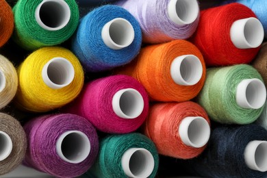 Photo of Top view of colorful sewing threads as background, closeup
