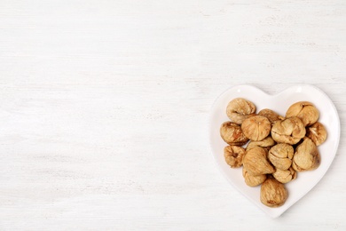 Photo of Plate of dried figs on white wooden table, top view with space for text. Healthy fruit