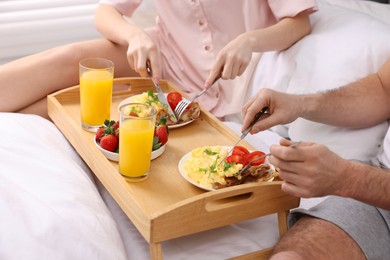 Couple eating tasty breakfast on bed, closeup