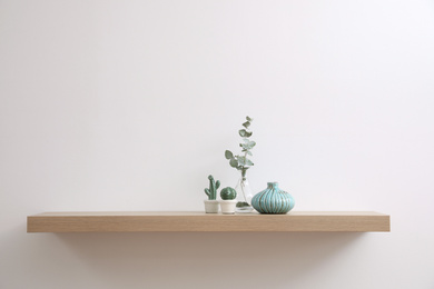 Photo of Wooden shelf with decorative elements on light wall