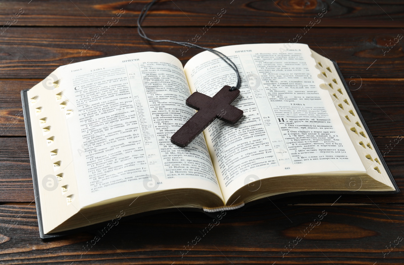 Photo of MYKOLAIV, UKRAINE - DECEMBER 21, 2021: Wooden cross and Bible on table, text in russian