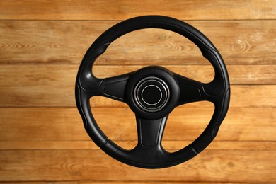 Photo of New black steering wheel on wooden background