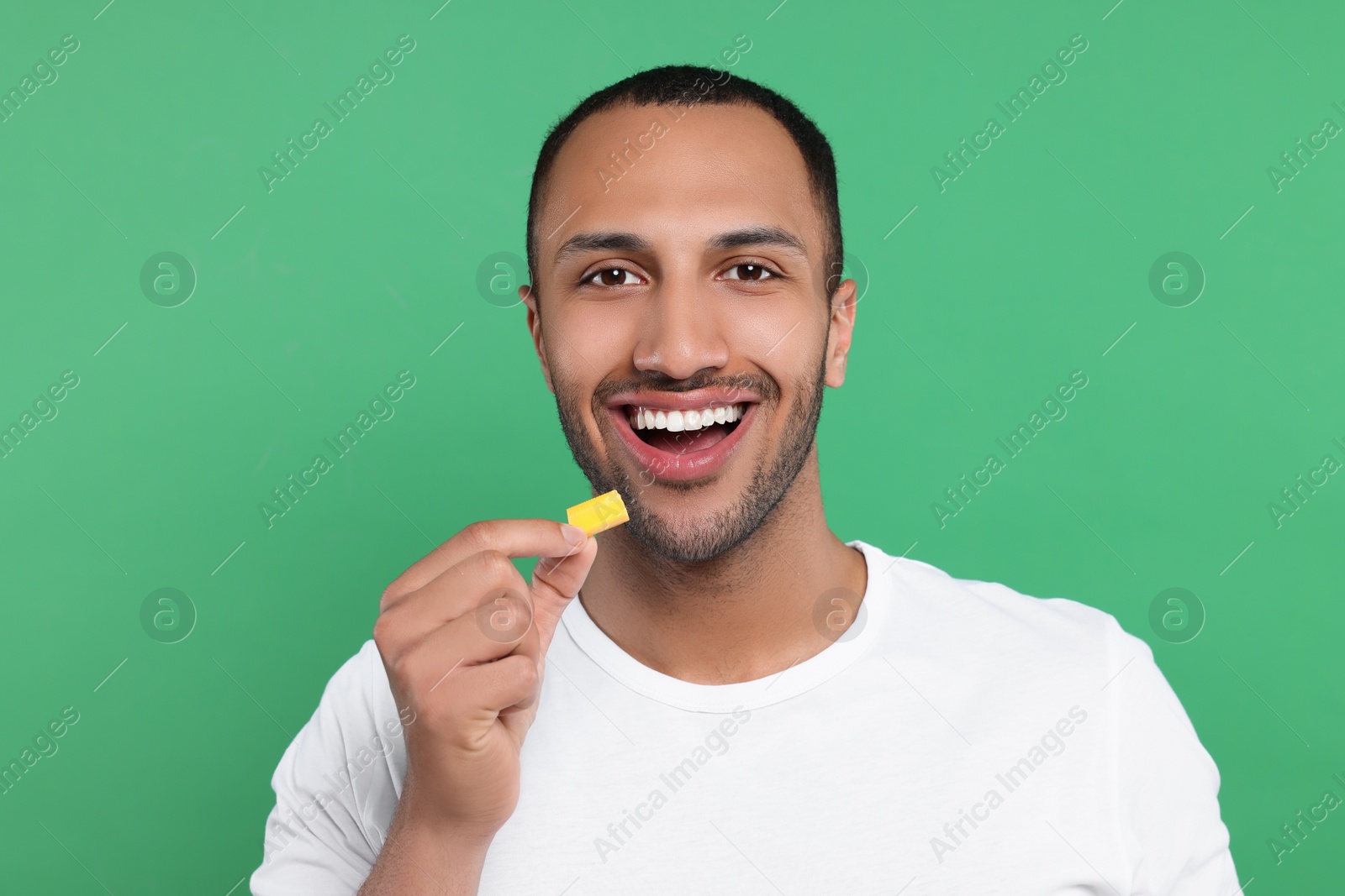 Photo of Portrait of happy young man with bubble gum on green background