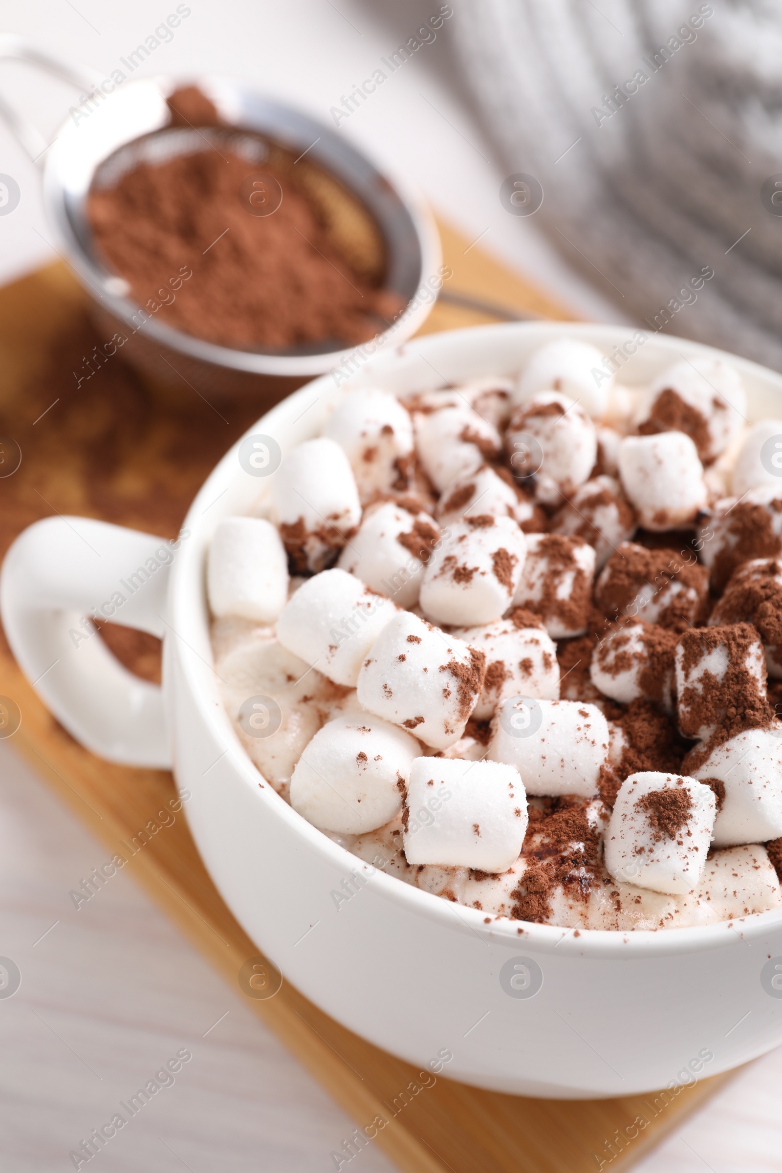 Photo of Cup of aromatic hot chocolate with marshmallows and cocoa powder on table, closeup