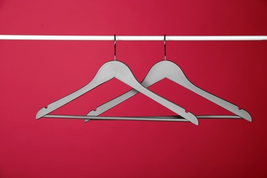 Photo of Empty clothes hangers on metal rail against color background