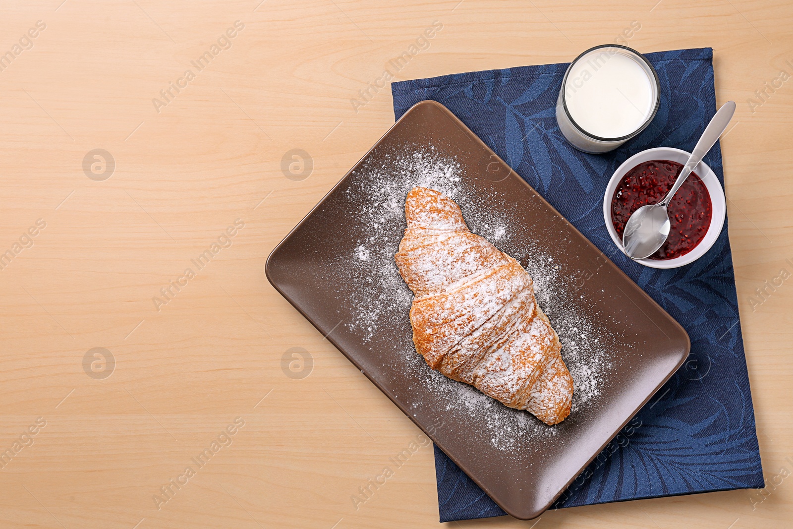 Photo of Plate with tasty croissant, glass of milk and jam on wooden background, top view