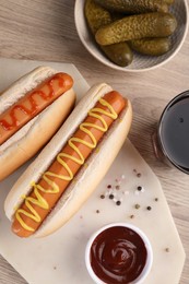 Photo of Tasty hot dogs with ketchup and mustard served on wooden table, flat lay