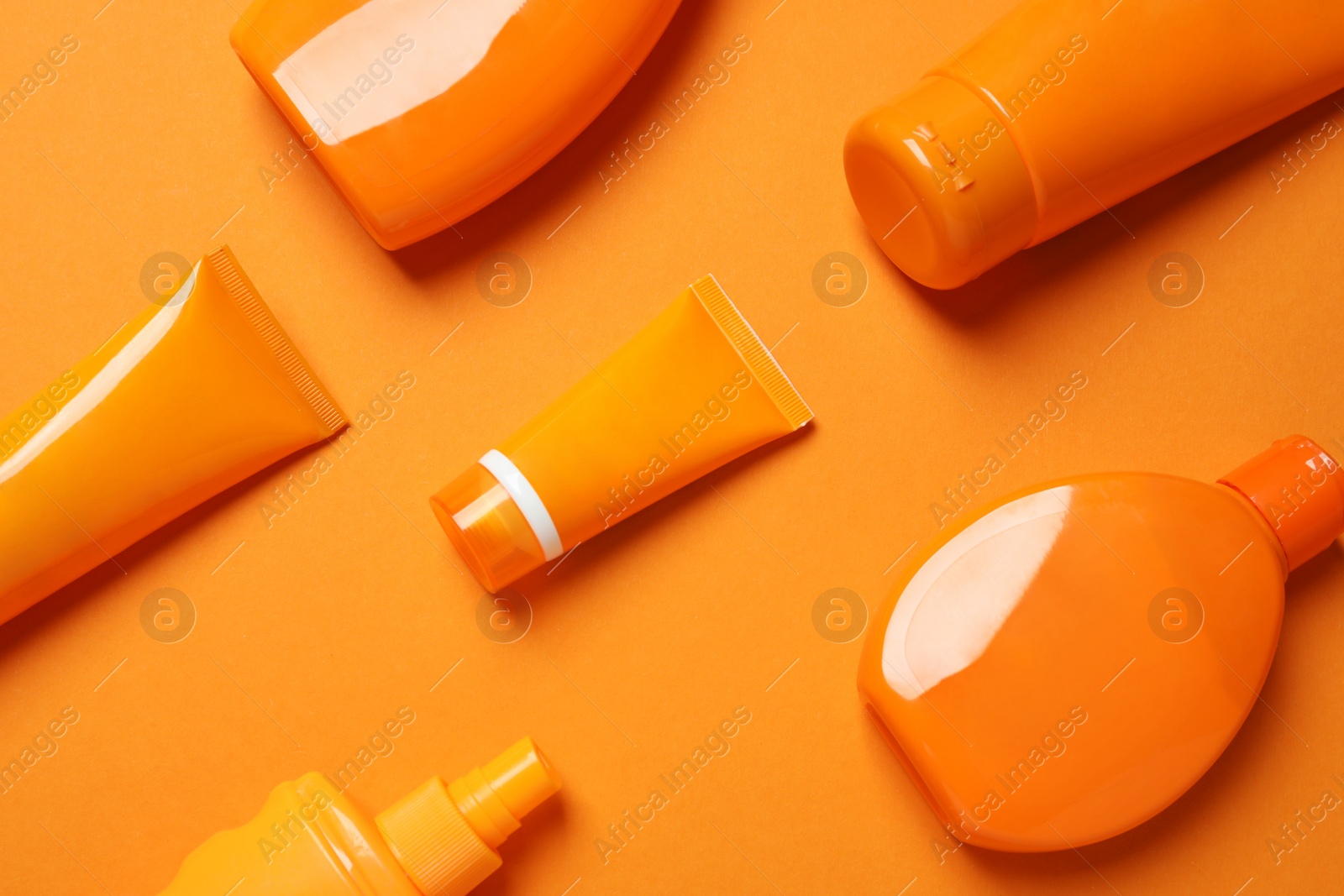 Photo of Flat lay composition with sun protection cosmetic products on orange background