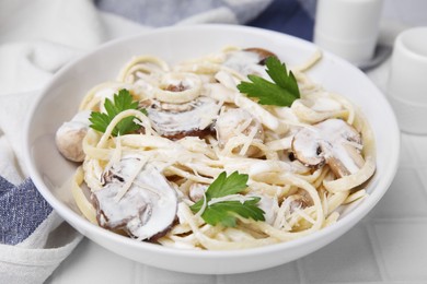 Delicious pasta with mushrooms on white tiled table, closeup