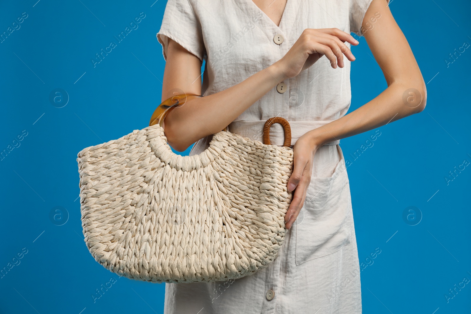 Photo of Young woman with stylish straw bag on blue background, closeup