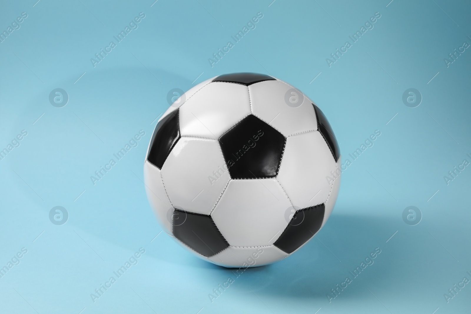 Photo of One soccer ball on light blue background. Sports equipment