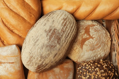 Photo of Different freshly baked breads as background, top view