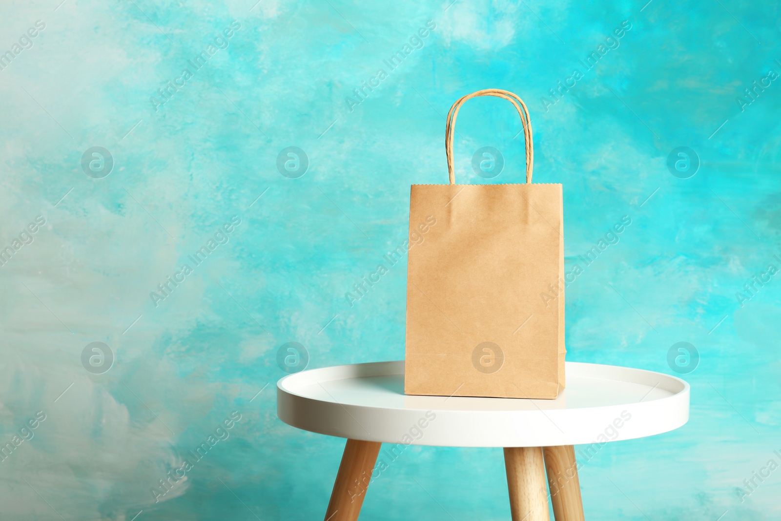 Photo of Mockup of paper shopping bag on table against color background