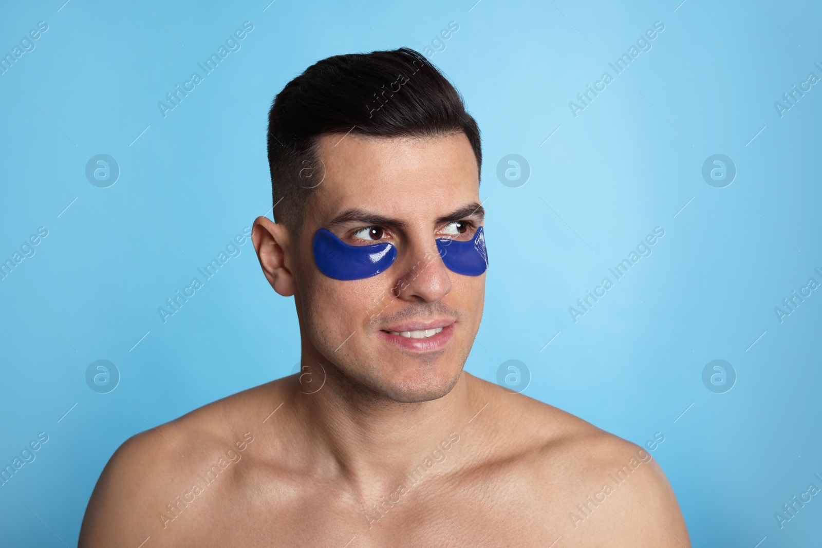 Photo of Man with under eye patches on light blue background