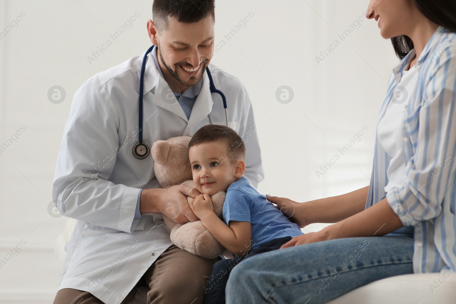 Photo of Mother and son visiting pediatrician in hospital. Doctor playing with little boy