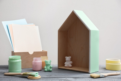 Photo of Brush with paint and model of house on grey wooden table