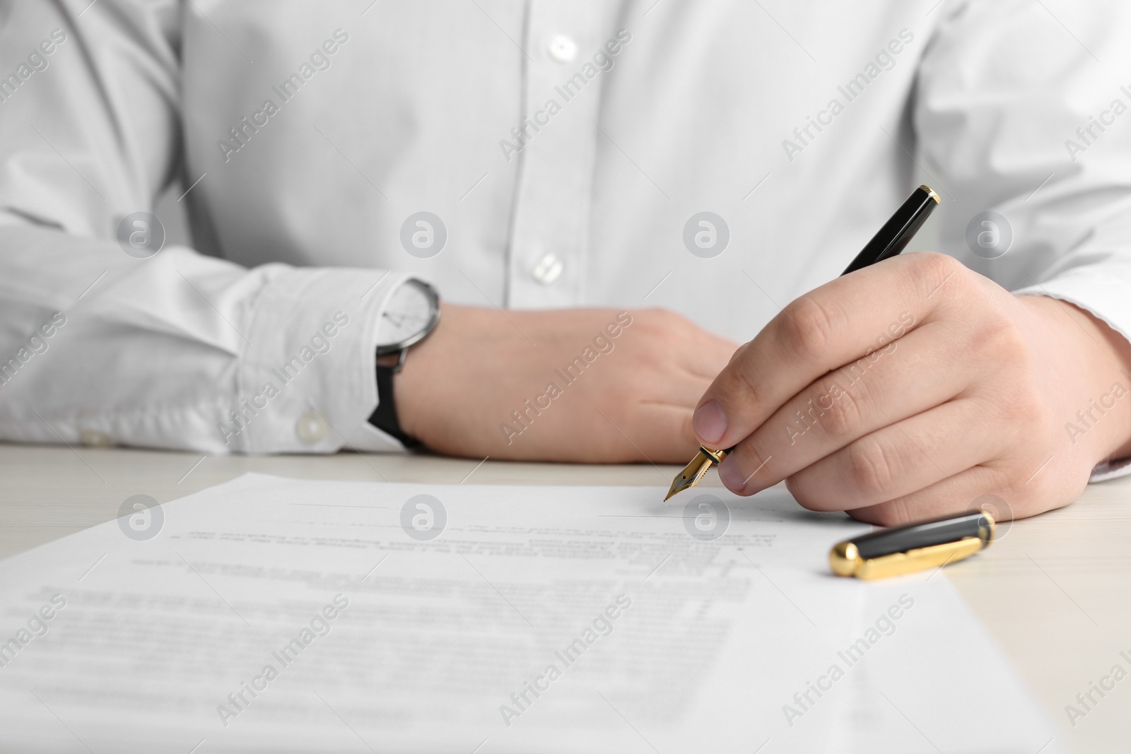 Photo of Notary signing document at wooden table, closeup