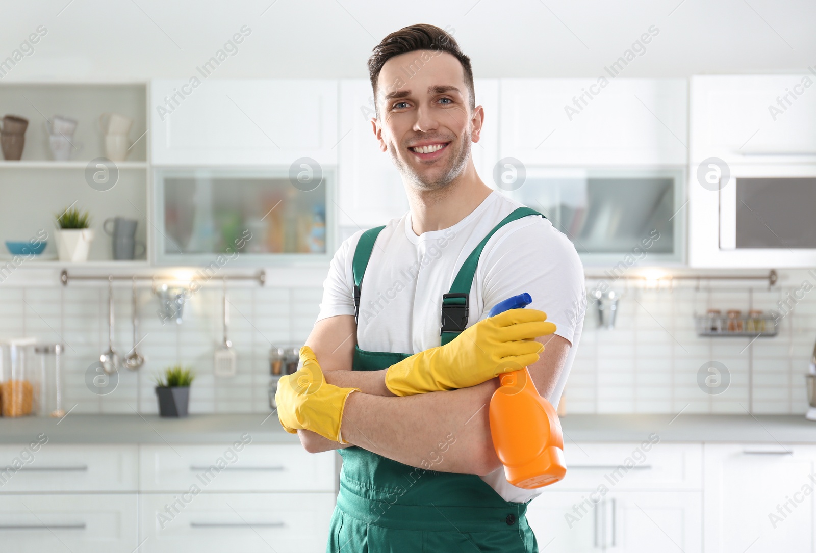 Photo of Portrait of janitor with sprayer in kitchen. Cleaning service