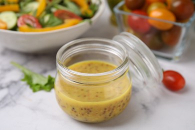 Photo of Tasty vinegar based sauce (Vinaigrette) in jar on white marble table, closeup