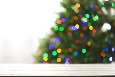 Photo of Empty table and blurred fir tree with colorful Christmas lights on background, bokeh effect. Space for design