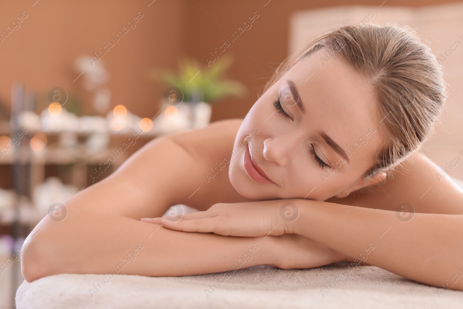 Photo of Young woman lying on massage table in spa salon