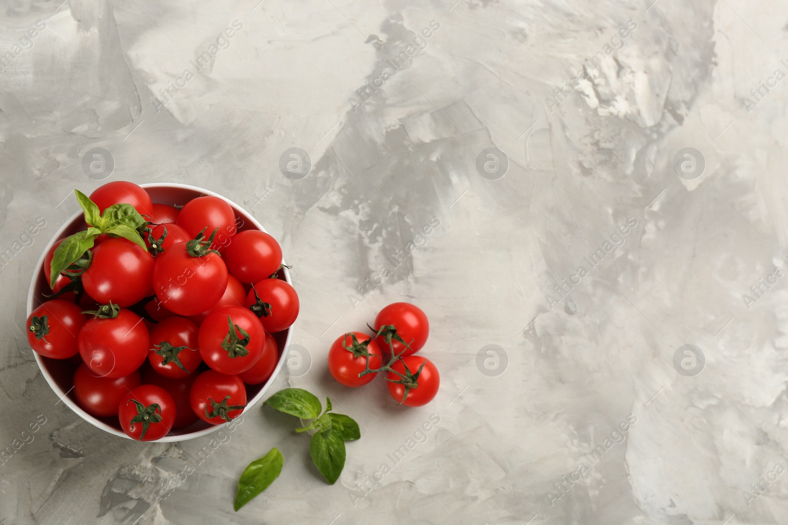 Photo of Fresh ripe cherry tomatoes and basil on light grey table, flat lay. Space for text