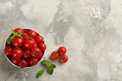 Fresh ripe cherry tomatoes and basil on light grey table, flat lay. Space for text