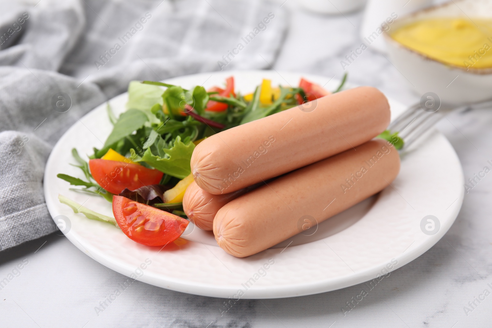 Photo of Delicious boiled sausages with salad on table