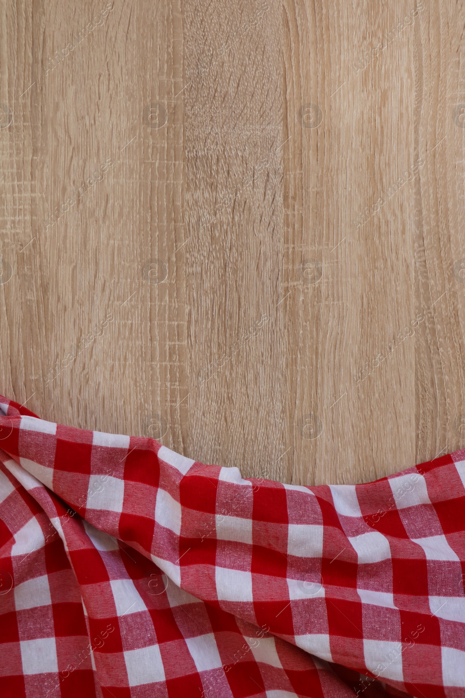 Photo of Checkered picnic cloth on wooden table, top view. Space for text