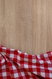 Checkered picnic cloth on wooden table, top view. Space for text