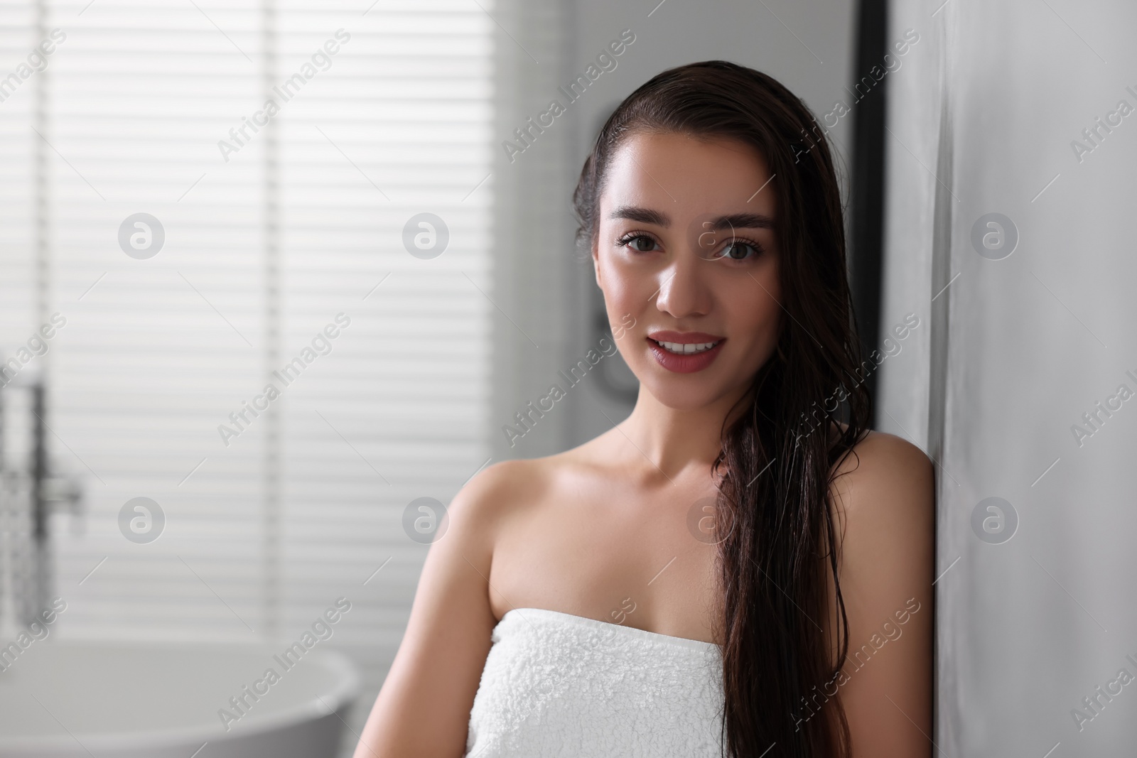 Photo of Smiling young woman after shower in bathroom. Space for text